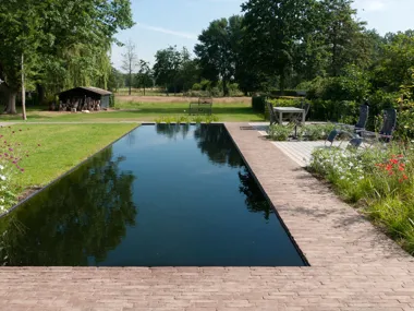 Zwemvijver omringd door kleiklinkers als schakel tussen tuin en landschap