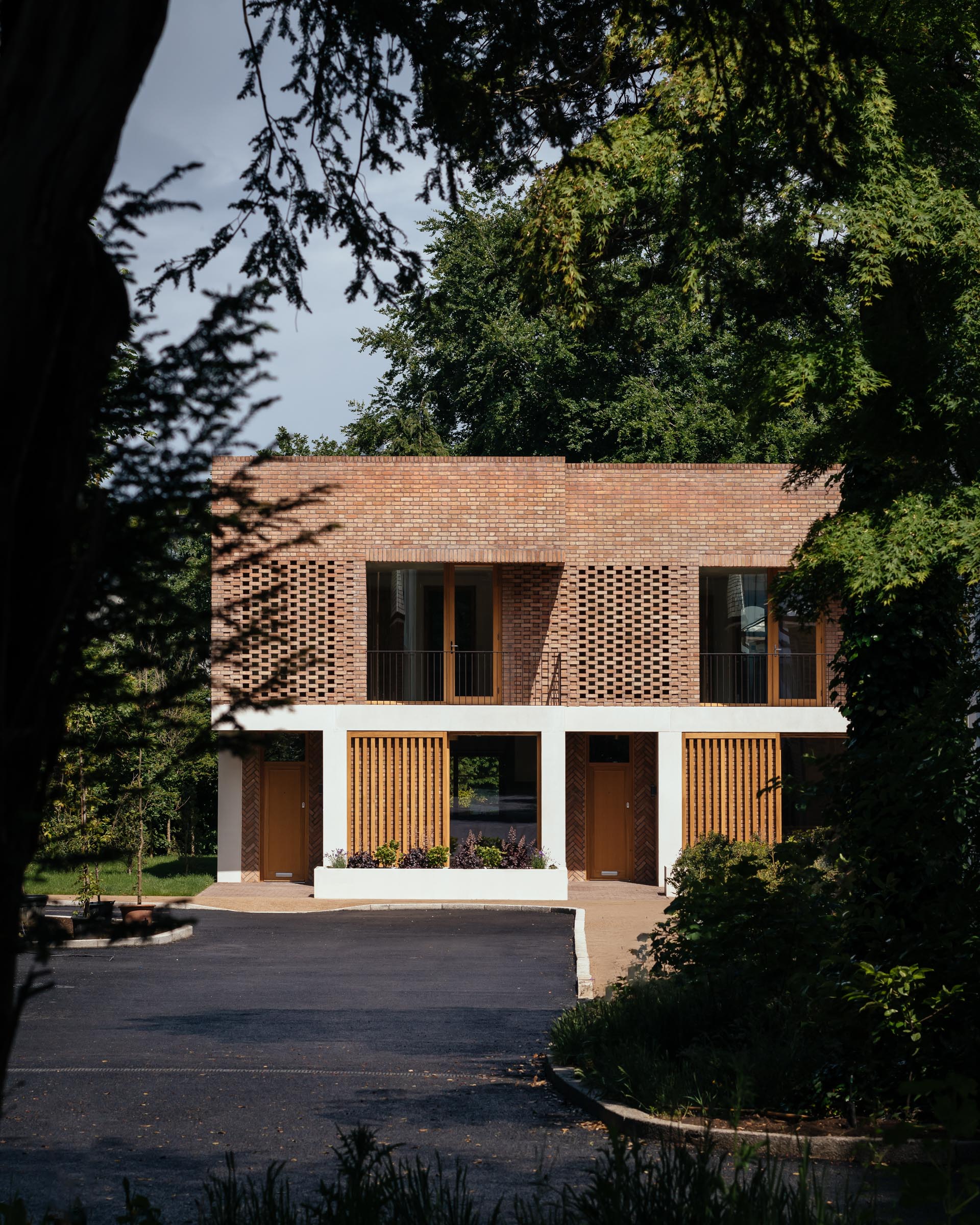 Verschillende artisanale gevelstenen verbinden woningen in een herwaardeerd bosrijk, Engels landgoed 